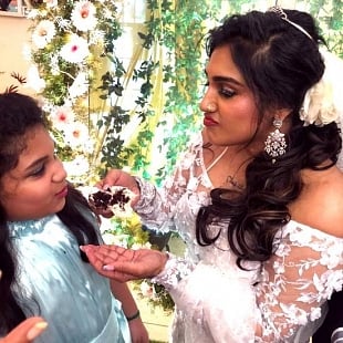 Vanitha lovingly feeding a piece of the cake to her daughter